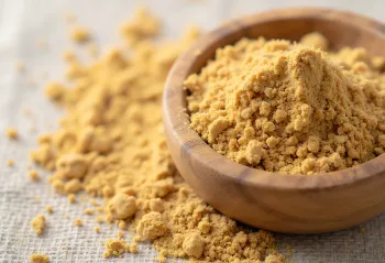 Ashwagandha pulber väikeses klaasis, maise pruuni värvusega, ümbritsetud värskete ashwagandha juurtega